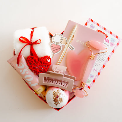Valentine’s Heart-shaped gift box with a rosewater hand lotion, facial roller and gua sha set, bath bomb, socks, notebook, and personalized greeting card